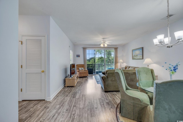 living room featuring hardwood / wood-style flooring and ceiling fan with notable chandelier