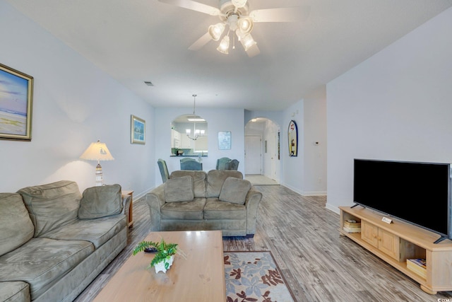 living room with hardwood / wood-style floors and ceiling fan with notable chandelier