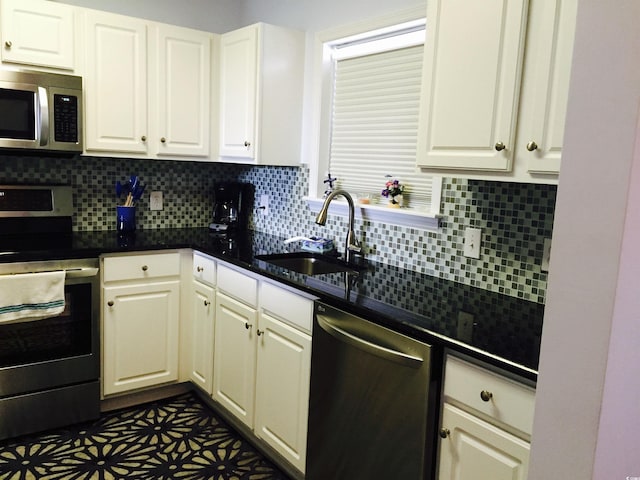 kitchen featuring white cabinetry, sink, tasteful backsplash, dark tile patterned floors, and appliances with stainless steel finishes