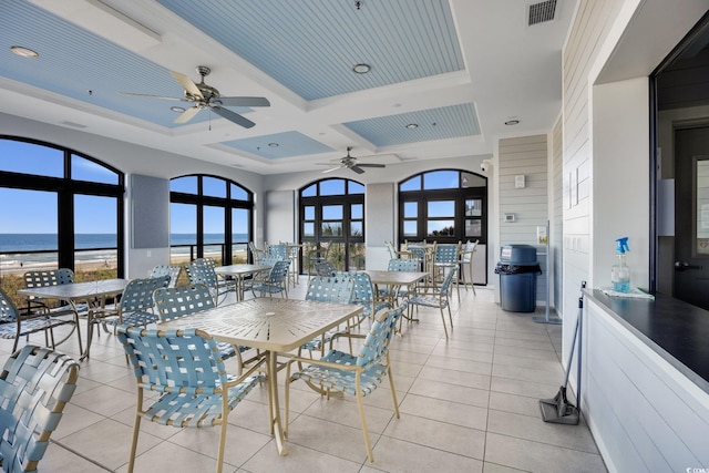 dining room featuring plenty of natural light, a water view, and light tile patterned floors