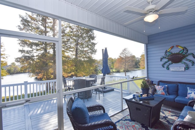 sunroom featuring ceiling fan and a water view