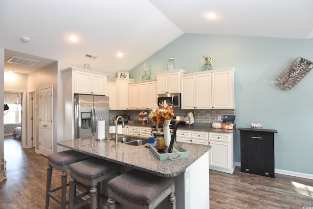 kitchen featuring stainless steel appliances, sink, a center island with sink, and a kitchen bar