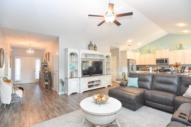 living room with hardwood / wood-style flooring, vaulted ceiling, and ceiling fan with notable chandelier