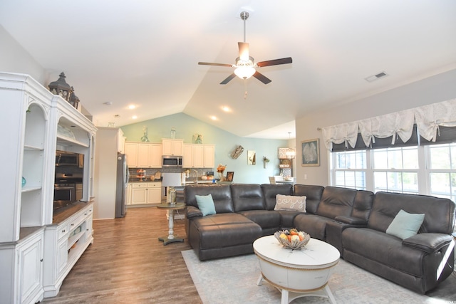 living room featuring ceiling fan, vaulted ceiling, and light wood-type flooring