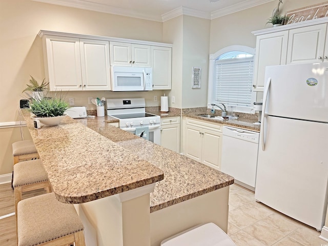 kitchen with a kitchen bar, kitchen peninsula, sink, white cabinetry, and white appliances