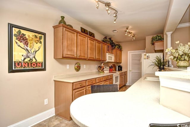 kitchen with decorative columns, white appliances, light tile patterned flooring, and rail lighting