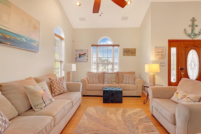 living room with high vaulted ceiling, ceiling fan, a healthy amount of sunlight, and light hardwood / wood-style flooring