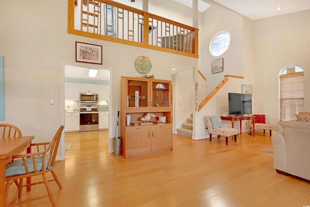 living room with light hardwood / wood-style floors and a high ceiling