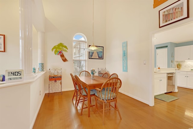 dining space with light hardwood / wood-style floors and a high ceiling