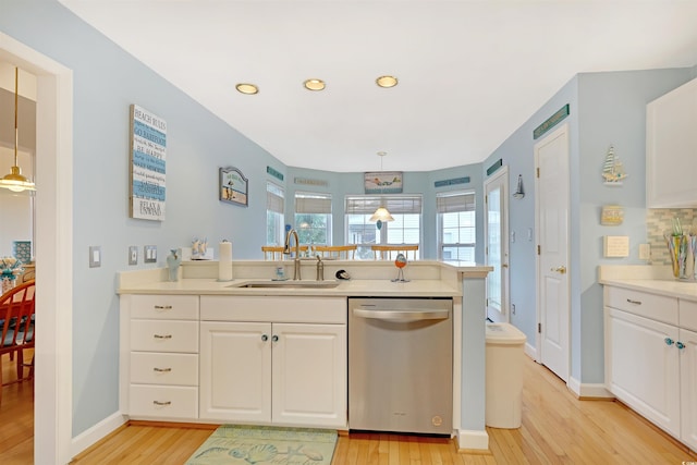 kitchen featuring dishwasher, decorative light fixtures, sink, and light hardwood / wood-style floors