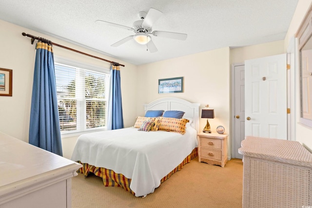 bedroom with ceiling fan, a textured ceiling, light carpet, and a closet