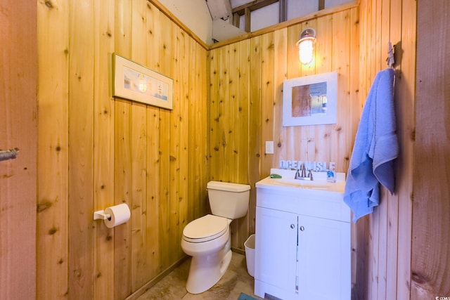 bathroom featuring vanity, wooden walls, and toilet