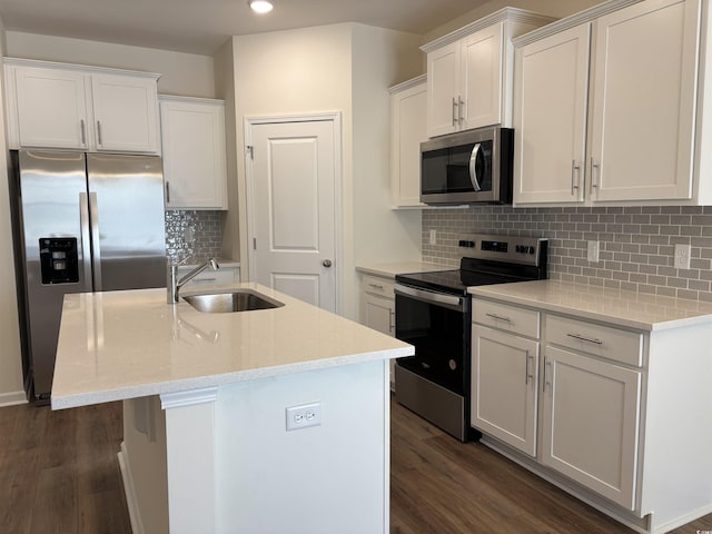 kitchen with appliances with stainless steel finishes, sink, a center island with sink, white cabinets, and dark hardwood / wood-style floors