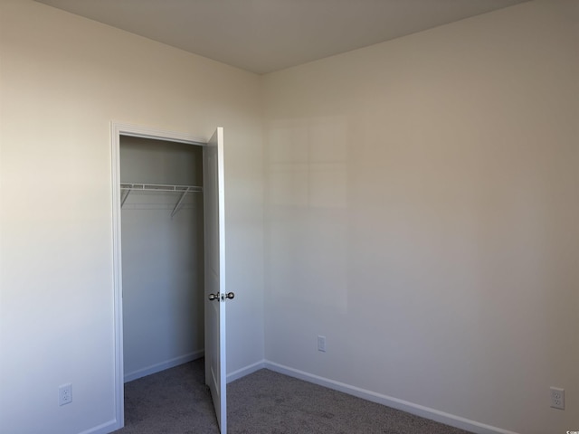 unfurnished bedroom featuring a closet and dark carpet