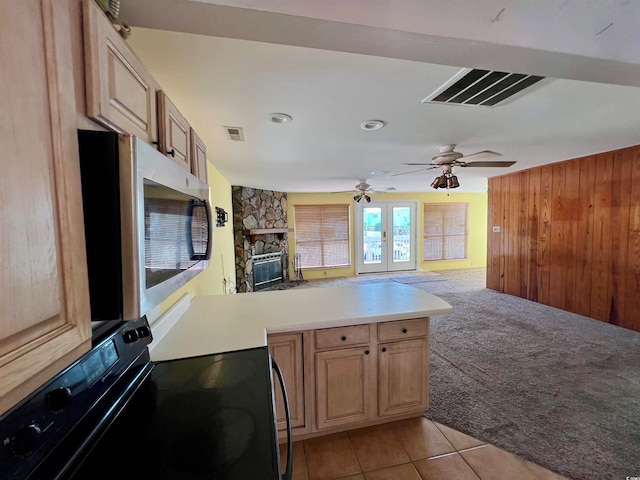 kitchen with black range with electric cooktop, wooden walls, light carpet, and kitchen peninsula