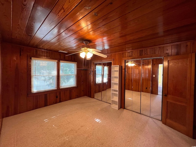 unfurnished bedroom with wood walls, wooden ceiling, ceiling fan, and carpet floors