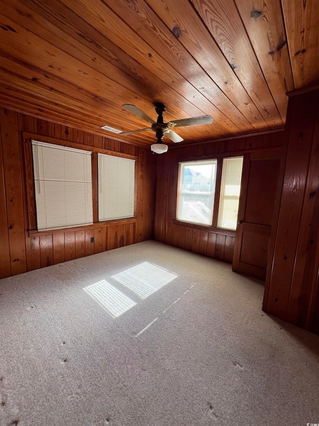 spare room featuring wooden walls, light carpet, ceiling fan, and wood ceiling