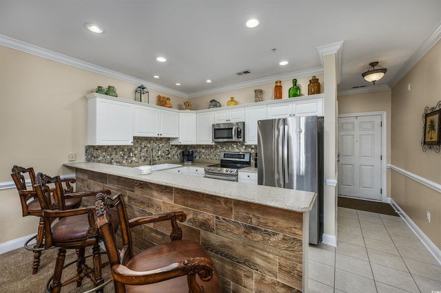 kitchen with white cabinets, kitchen peninsula, crown molding, light stone countertops, and appliances with stainless steel finishes