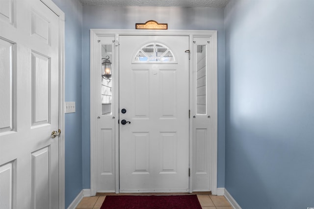 foyer with light tile patterned flooring, baseboards, and a textured ceiling