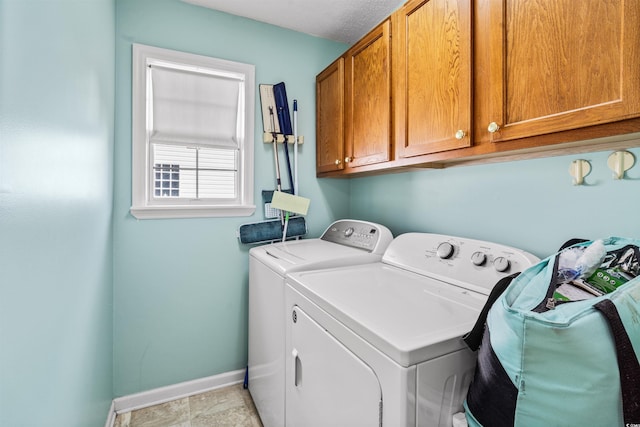 clothes washing area featuring washer and dryer, baseboards, and cabinet space