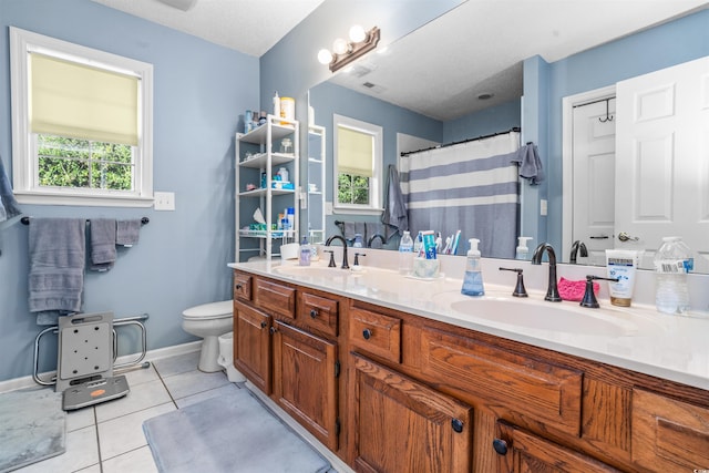 bathroom with toilet, tile patterned flooring, plenty of natural light, and double vanity