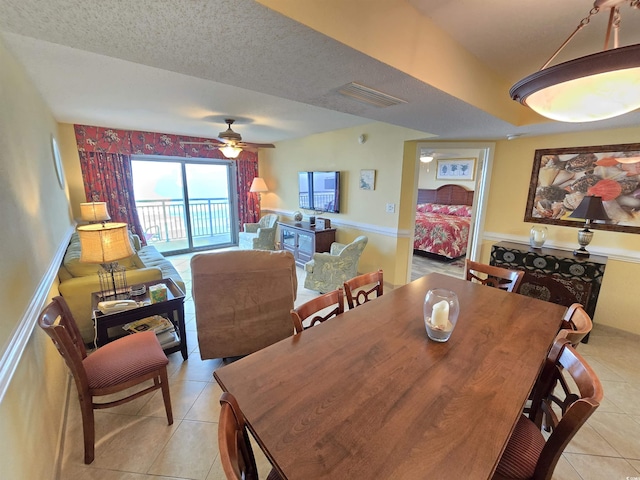 tiled dining room featuring ceiling fan and a textured ceiling