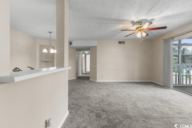 carpeted spare room featuring ceiling fan with notable chandelier and a textured ceiling