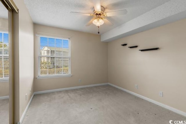 unfurnished room with ceiling fan, a textured ceiling, and light carpet