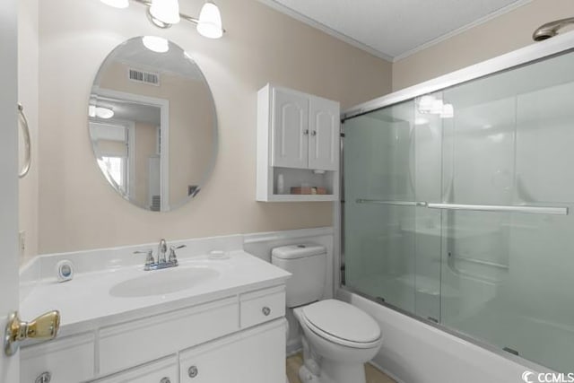 full bathroom featuring toilet, combined bath / shower with glass door, vanity, and crown molding