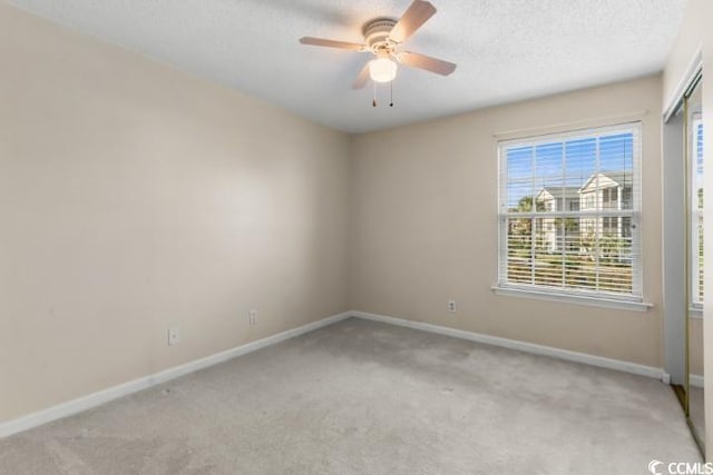 carpeted spare room featuring a textured ceiling and ceiling fan