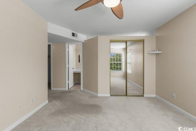 unfurnished bedroom featuring ceiling fan, light colored carpet, and a closet