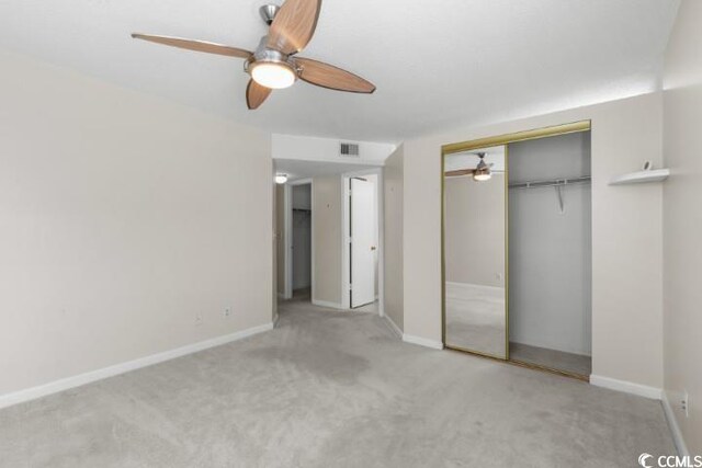 unfurnished bedroom with carpet floors, ceiling fan, and a closet