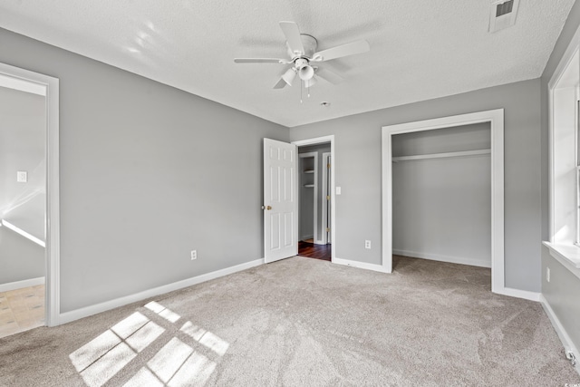 unfurnished bedroom featuring ceiling fan, a closet, light carpet, and a textured ceiling