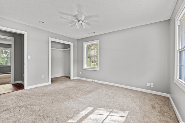 unfurnished bedroom with carpet flooring, a closet, multiple windows, and ceiling fan