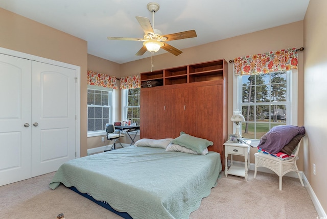 carpeted bedroom with a closet, multiple windows, and ceiling fan