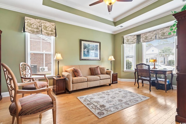 living room with ceiling fan, a raised ceiling, light hardwood / wood-style floors, and crown molding