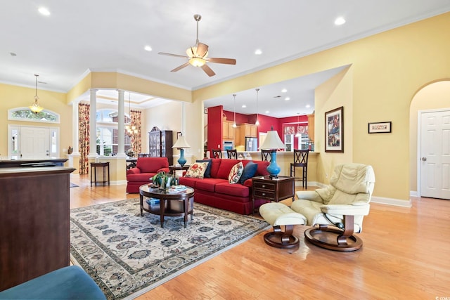 living room featuring light wood-type flooring, ornate columns, ceiling fan, and ornamental molding