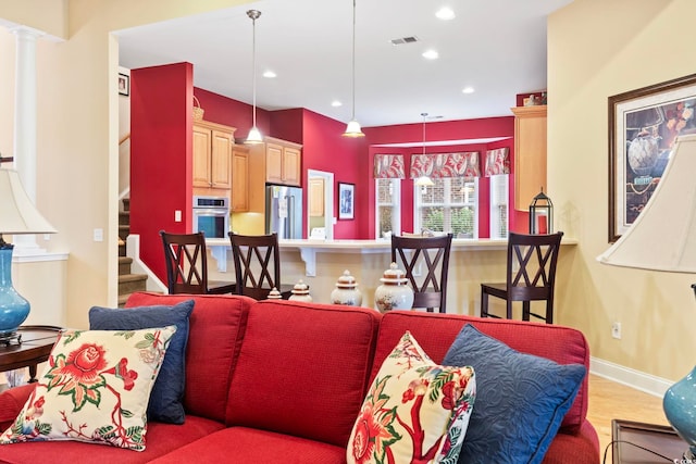 living room featuring light hardwood / wood-style floors and decorative columns