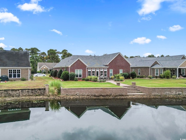 back of property featuring a lawn and a water view