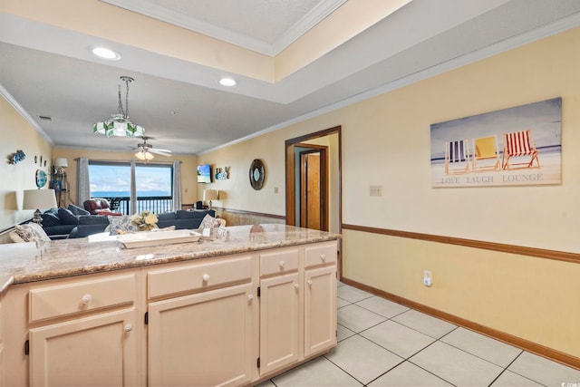 kitchen featuring cream cabinets, ornamental molding, light stone countertops, ceiling fan, and light tile patterned floors