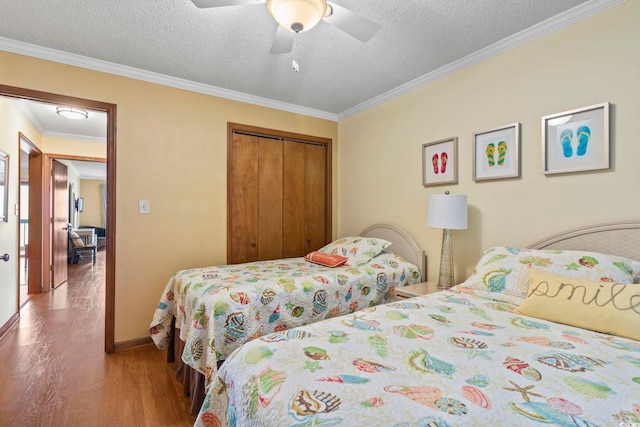 bedroom with hardwood / wood-style flooring, ceiling fan, a textured ceiling, crown molding, and a closet