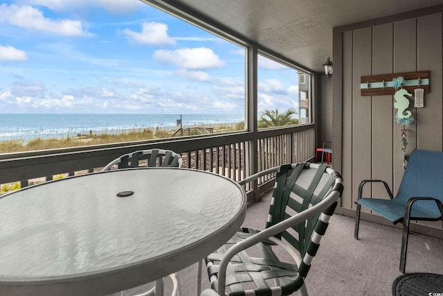 sunroom with a water view and a beach view