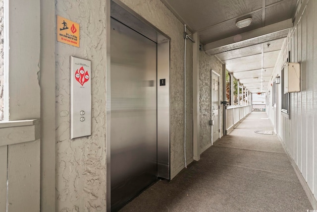 corridor featuring elevator and light colored carpet