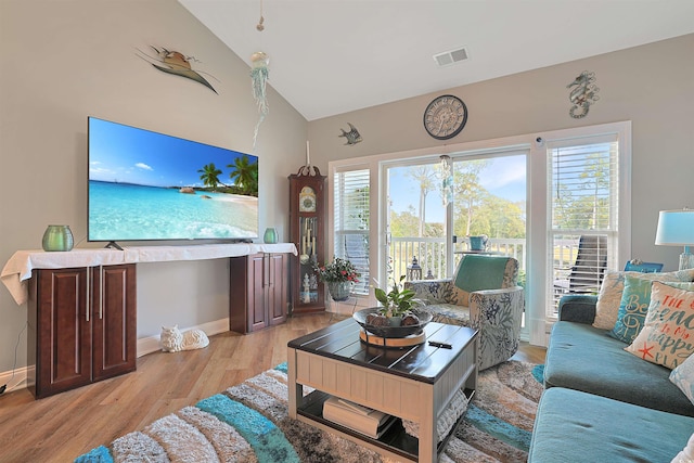 living room with light hardwood / wood-style flooring and high vaulted ceiling