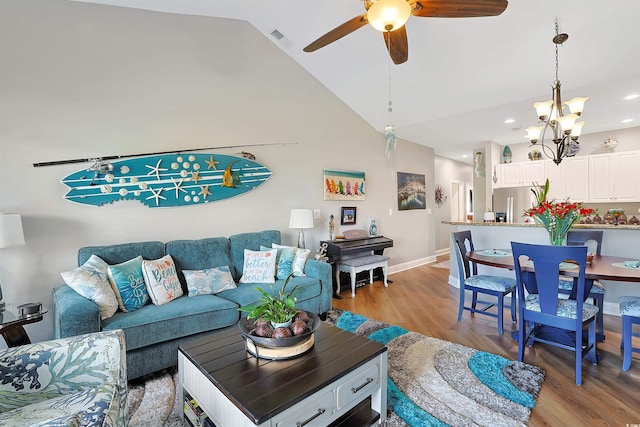 living room with high vaulted ceiling, light hardwood / wood-style floors, and ceiling fan with notable chandelier