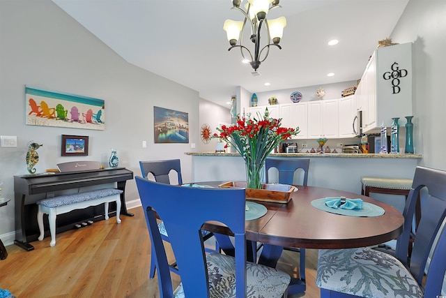 dining space with light wood-type flooring and an inviting chandelier