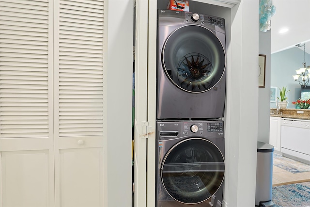 laundry area with stacked washing maching and dryer and a notable chandelier