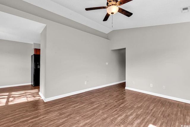 empty room featuring dark wood-type flooring, vaulted ceiling, and ceiling fan