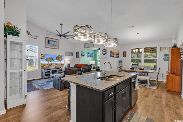 kitchen featuring hanging light fixtures, a center island with sink, sink, and light wood-type flooring