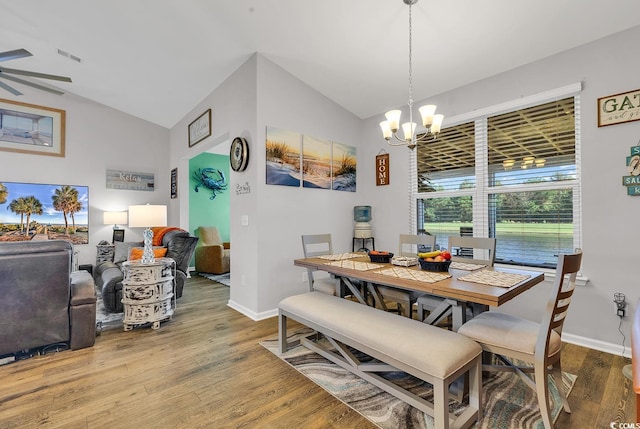 dining area featuring wood-type flooring, ceiling fan with notable chandelier, and lofted ceiling